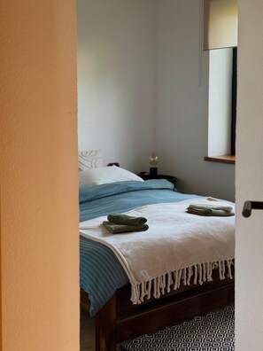 Un dormitorio con una cama, una mesita de noche, una lámpara y un espejo.
