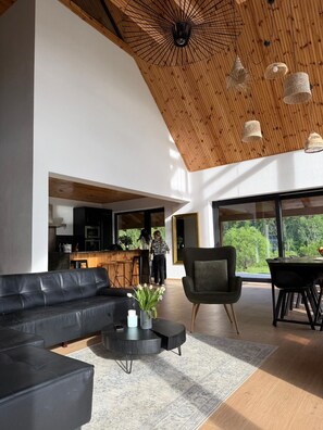 A modern living room with a black leather sofa, a coffee table, and a dining area with a table and chairs.