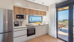 A modern kitchen with a built-in oven, microwave, and a large window overlooking a scenic view. - Villa Turística Palomas Torrox by Ruralidays (Málaga)