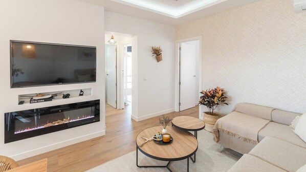 A modern living room with a flat-screen TV, fireplace, sofa, and a small round table. - Villa Turística Palomas Torrox by Ruralidays (Málaga)