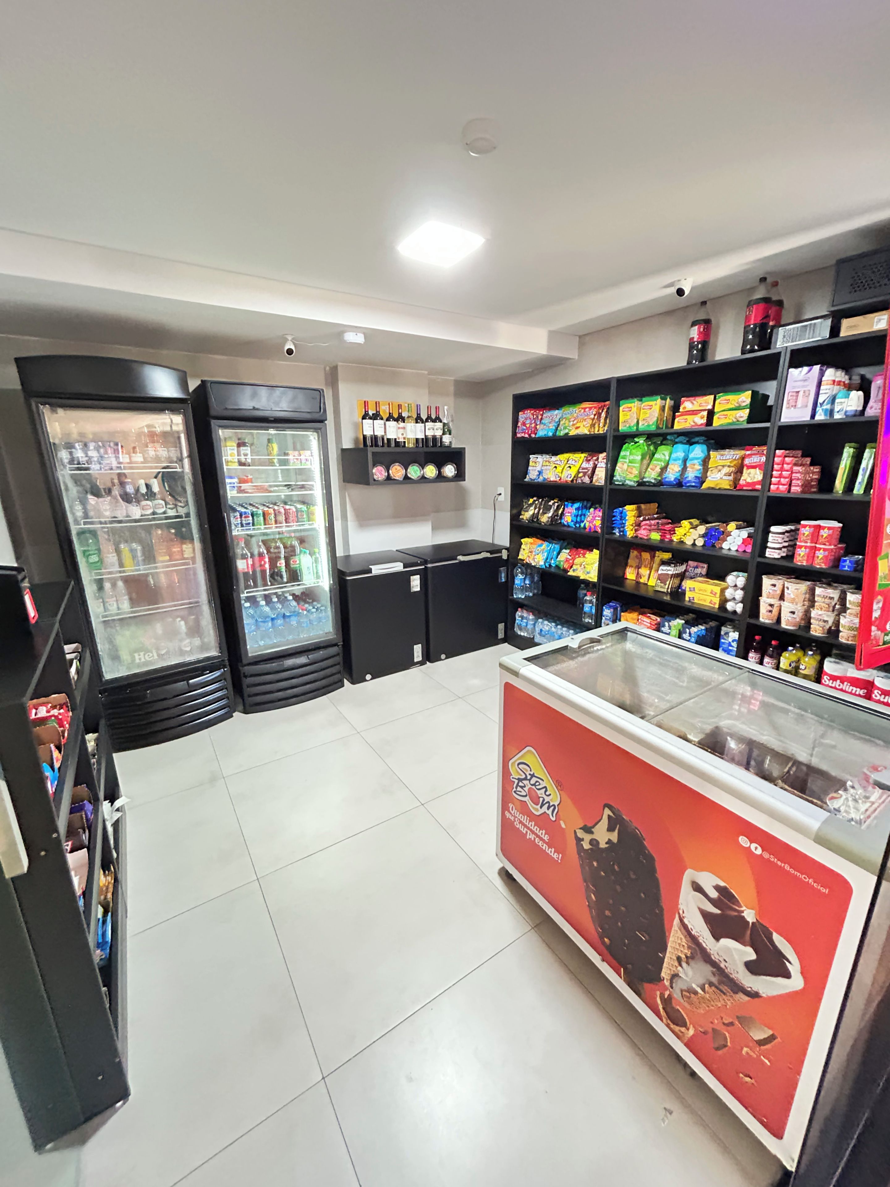 Una tienda de conveniencia con dispensadores de bebidas refrigeradas, estantes llenos de aperitivos y bebidas, y una sección de congelados.