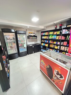 Ein Convenience Store mit gekühlten Getränkeautomaten, Regalen voller Snacks und Getränke sowie einer Gefriertruhe.