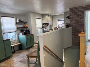 A kitchen with green cabinets, a microwave, and a wooden bench.