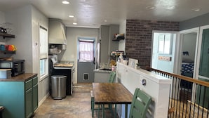 Cocina compacta con zona de comedor, un cesto de basura y una ventana con cortinas.