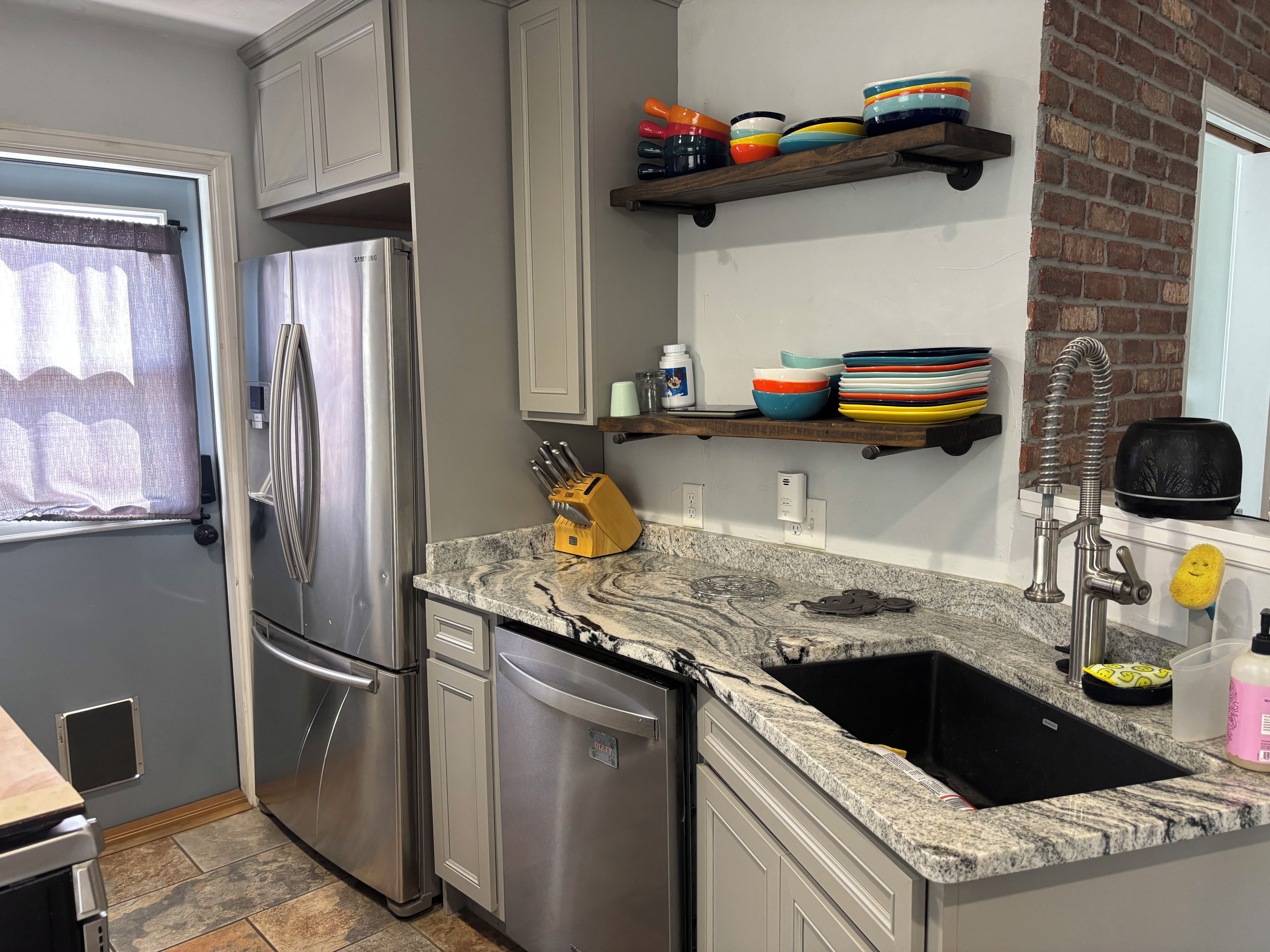 A kitchen with stainless steel appliances, a granite countertop, and a black sink.