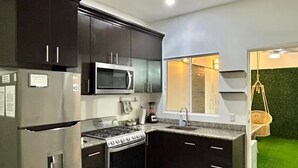 A modern kitchen with dark cabinetry, stainless steel appliances, and a tiled floor.