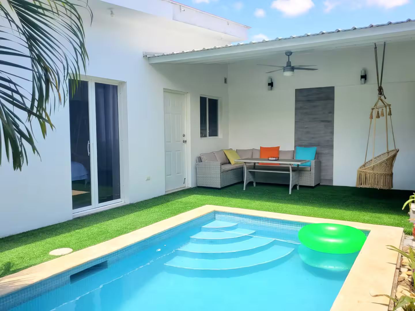 Ein Wohnhaus mit Schwimmbad, überdachter Terrasse und einer Sitzecke.