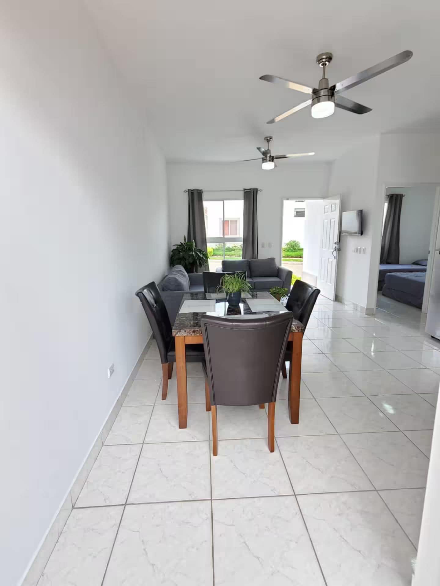 Ein stilvoller Essbereich mit Tisch, Stühlen und Deckenventilatoren.