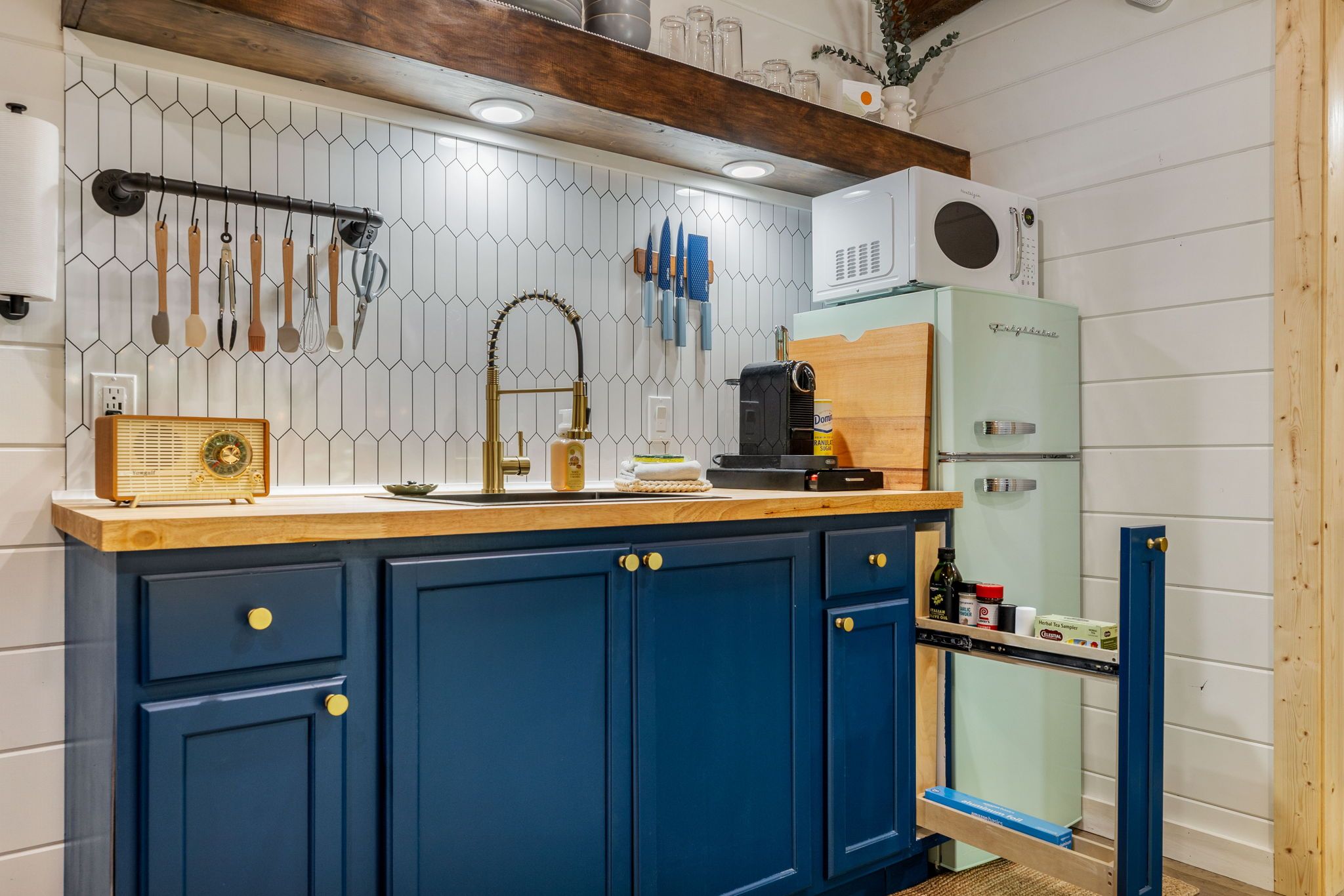 A kitchen with a blue cabinet, a wooden countertop, a vintage radio, and a modern coffee maker.