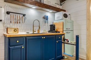 Eine Küche mit einem blauen Schrank, einer Holz Arbeitsplatte, einem alten Radio und einer modernen Kaffeemaschine.