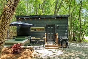 Eine Hütte mit Terrasse, Sitzgelegenheit im Freien, Grill und Whirlpool.