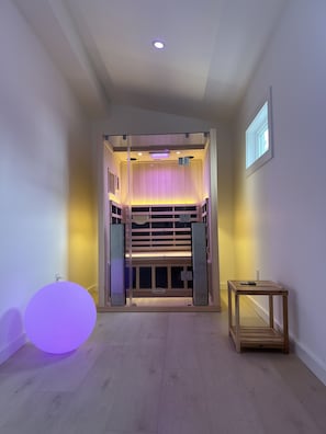 A room with a wooden floor, a small table with a remote, and a wall-mounted projector.