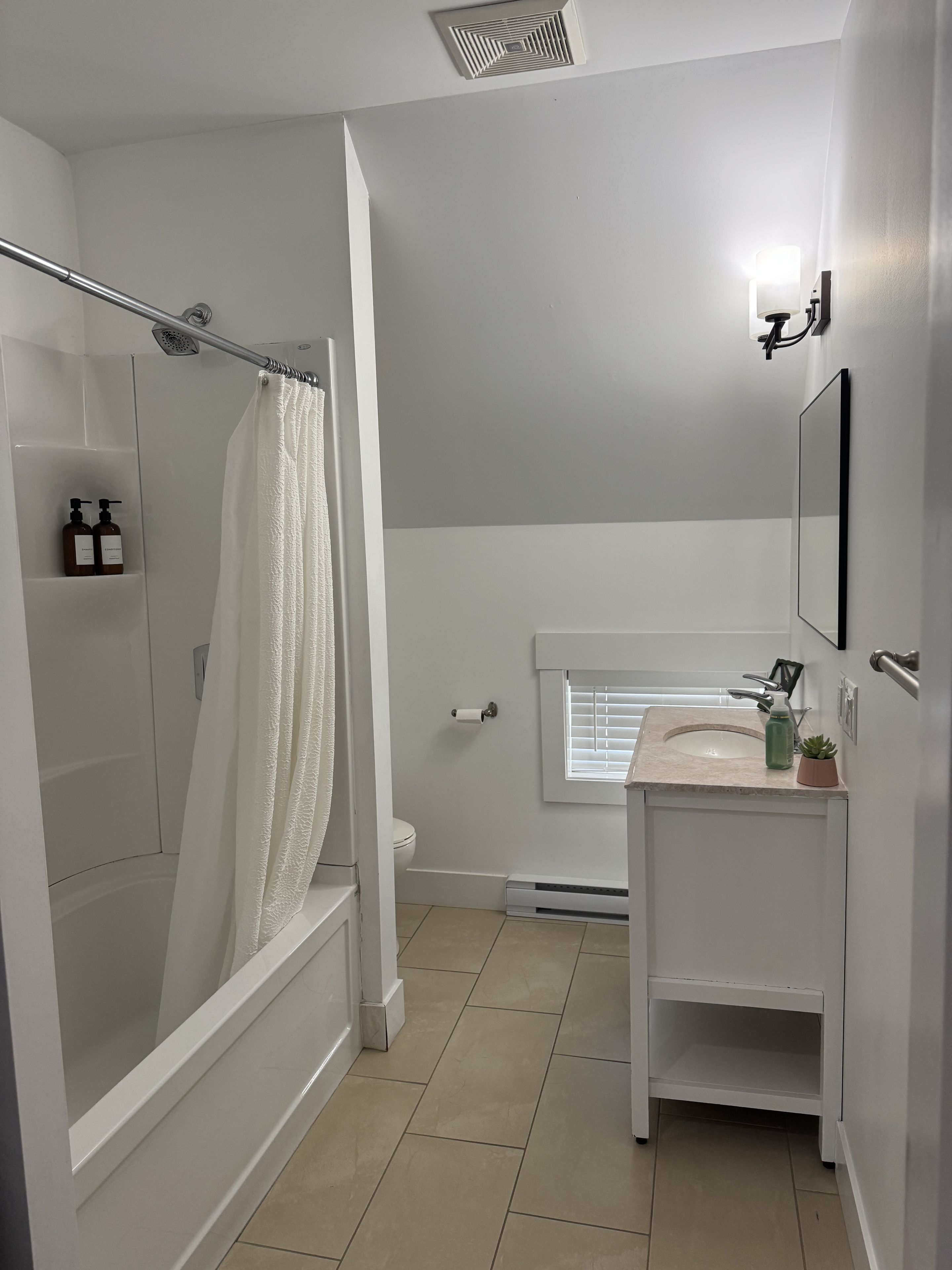 A modern bathroom with a shower, toilet, and sink.