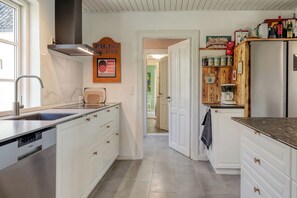 Eine moderne Küche mit weißen Schränken, einem eingebauten Geschirrspüler und einem Holzspeisekammer.