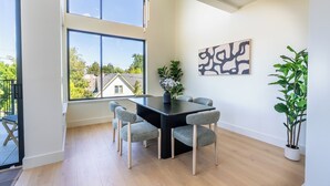 A dining area with a black table and grey chairs, a potted plant, and a wall-mounted abstract art piece. - Designer Townhome Near UO, 3 King Suites + Chefs Kitchen (Eugene)