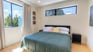 A bedroom with a large bed, a window with curtains, a bedside table, and a wall-mounted shelf. - Designer Townhome Near UO, 3 King Suites + Chefs Kitchen (Eugene)