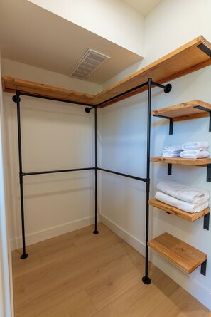 Ein Eckzimmer mit Holzboden, einem schwarzen Metallgestell und Regalen mit gefalteten Handtüchern.