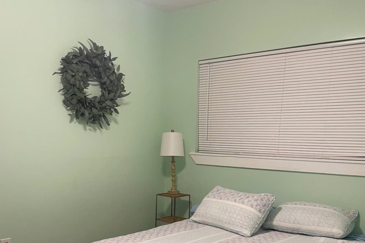 Un dormitorio con cama, lámpara de noche, aplique de pared y una guirnalda decorativa.