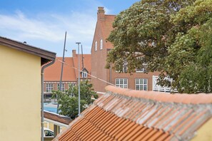 A residential building with a red-tiled roof, a brick facade, and a large tree in the foreground. - Lovely apartment in the heart of Skagen town (Skagen)
