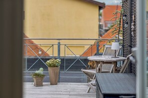 Eine Holzterrasse mit zwei Blumentöpfen, einem runden Tisch und einem Stuhl.