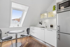 Eine moderne Küche mit Oberlichter, weißen Schränken, einem Kühlschrank und einem Essbereich mit Tisch und Stühlen.