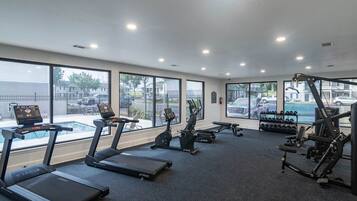 Un gimnasio con cintas de correr, elípticas y equipo de pesas.