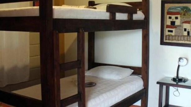 Un lit superposé avec une tête de lit, une petite table de chevet et une lampe fixée au mur.