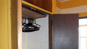 Une pièce avec une armoire en bois, un mur en briques blanches et une porte sombre.