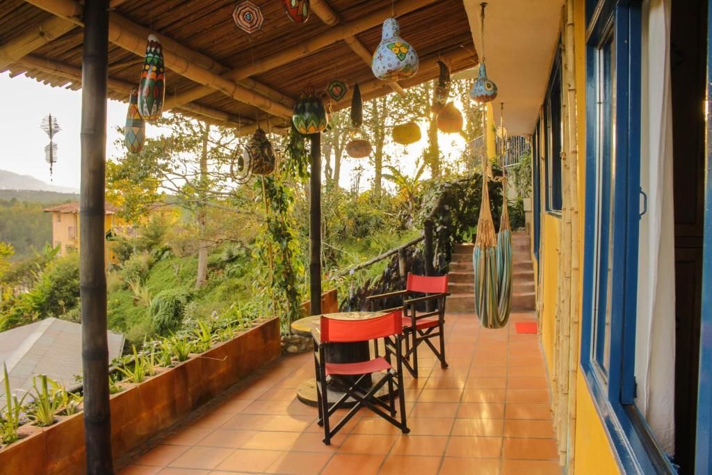 A covered outdoor seating area with chairs and tables, surrounded by greenery and a view of the landscape.