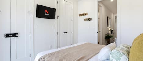 A bedroom with a bed, a TV mounted on the wall, and a door with a handle.