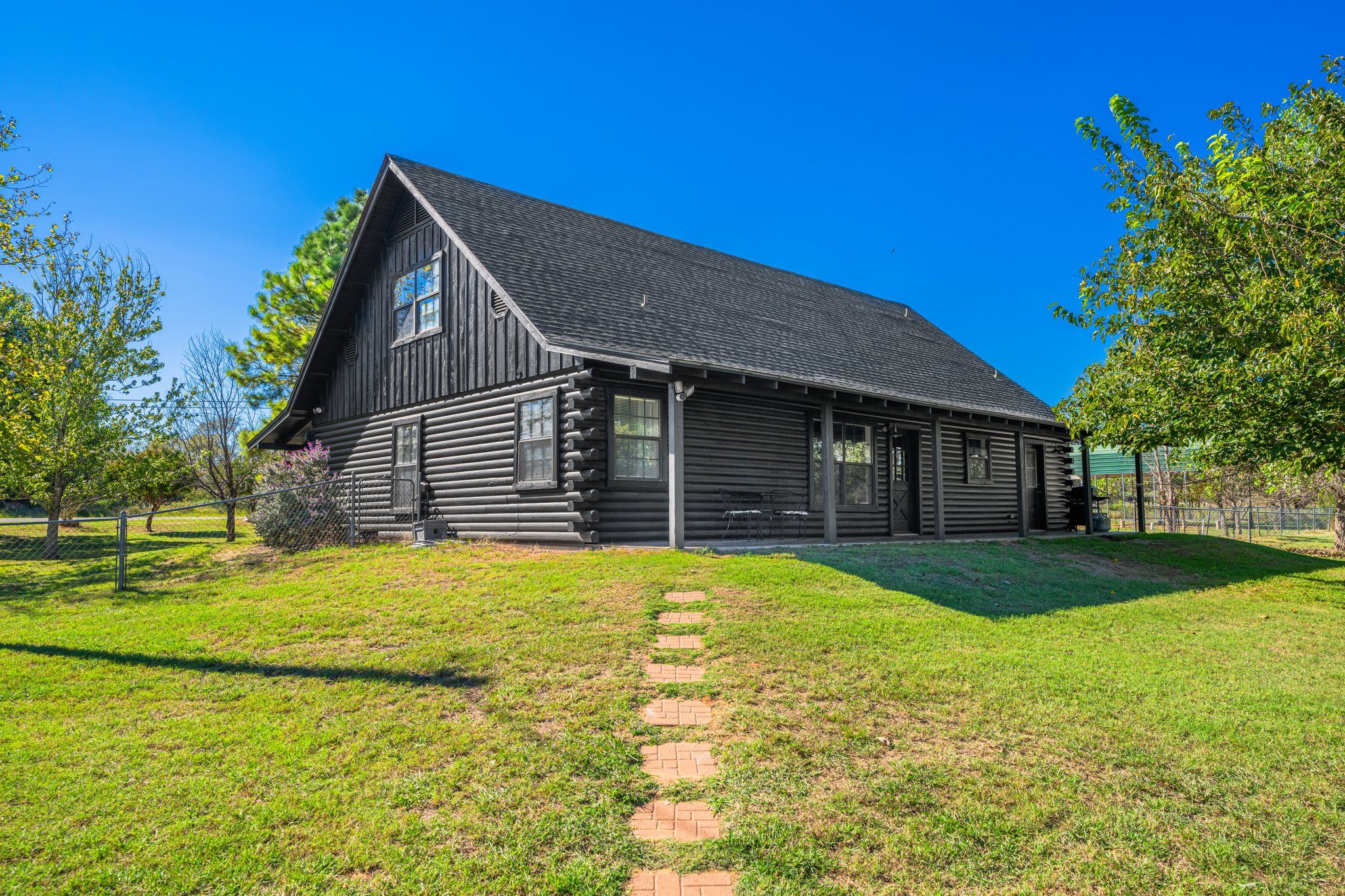 A log cabin with a steep gabled roof, a front porch, and a brick pathway leading to the entrance.