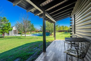 Un patio techado con una mesa y sillas, una piscina y un jardín cubierto de césped.
