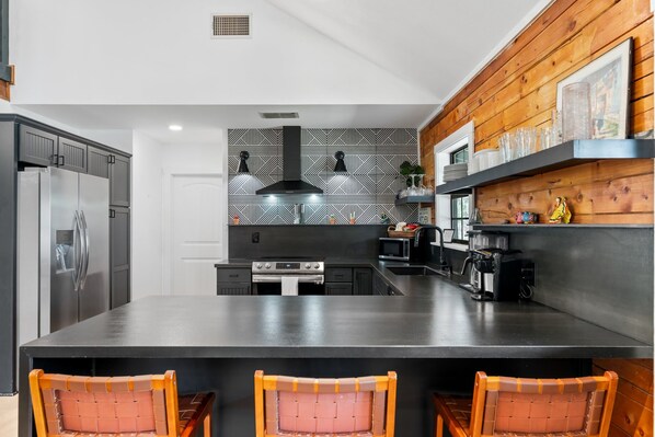A modern kitchen with a large island, stainless steel appliances, and a geometric backsplash. - Casa Boots & Bubbly w/ Pool, Sleeps 14 (Fredericksburg)