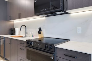A modern kitchen with a built-in stove, oven, and microwave, stainless steel appliances, and wooden cabinets. - Luxury Condo With Pool-view Balcony (New Braunfels)