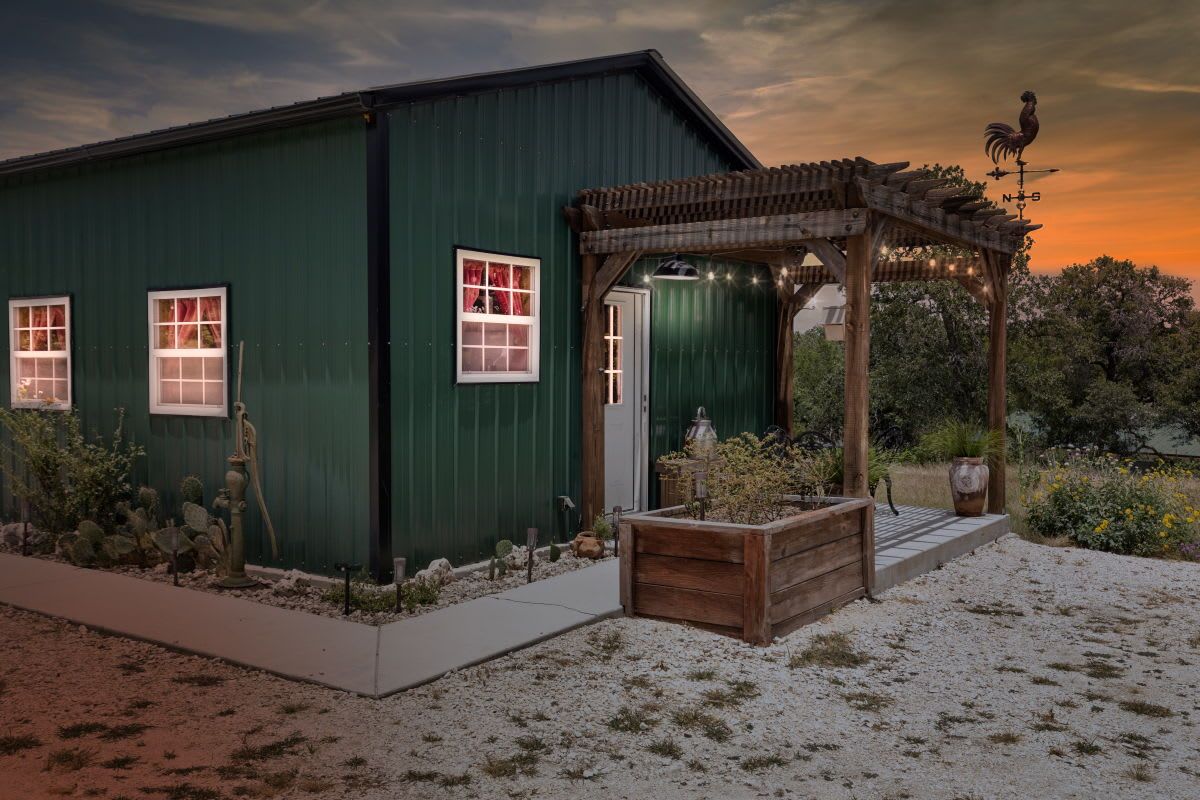 A green building with a wooden pergola, a door, and windows.