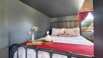 Ein Schlafzimmer mit einem Bett, einem Nachttisch, einer Blumenvase und einem Fenster mit Vorhängen.