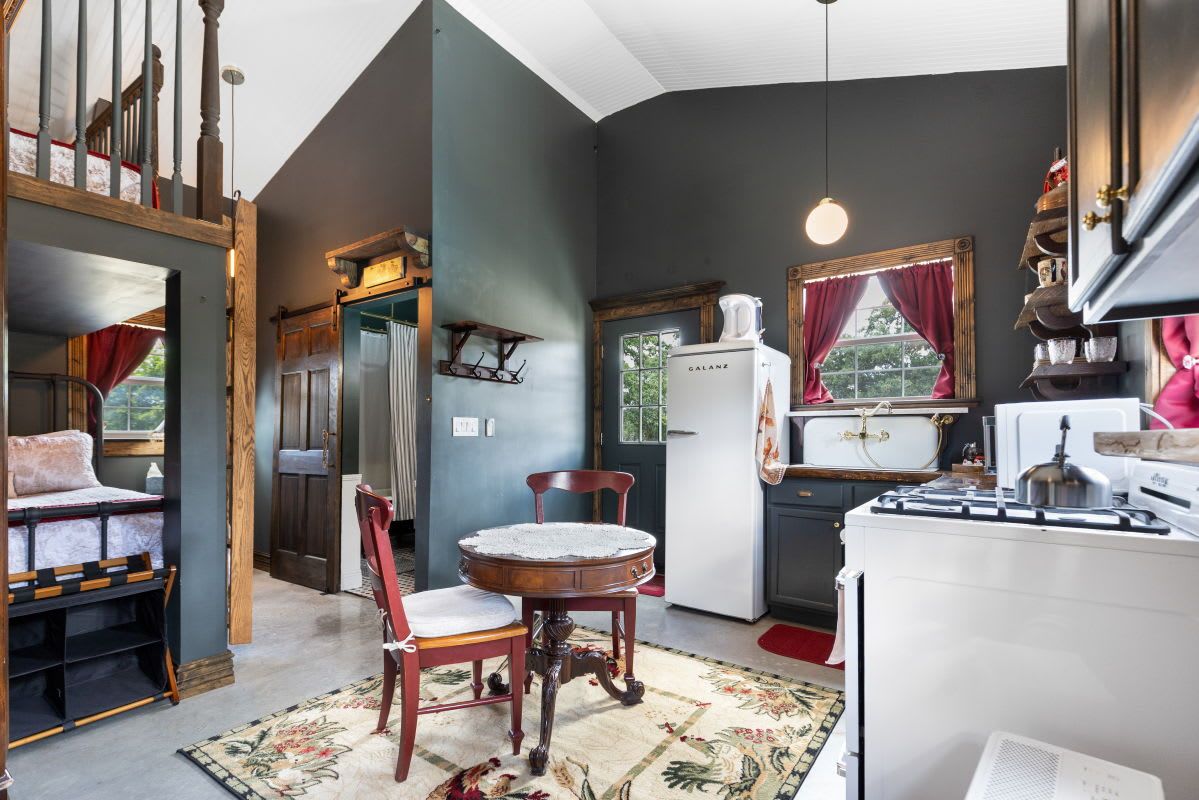 A cozy kitchen with a dining area, a refrigerator, and a window with curtains.