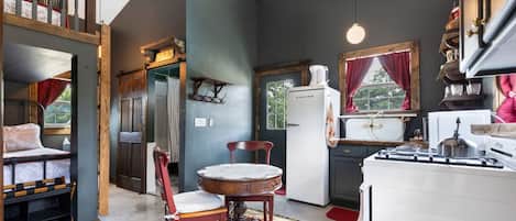 Uma cozinha acolhedora com área de jantar, geladeira e janela com cortinas.