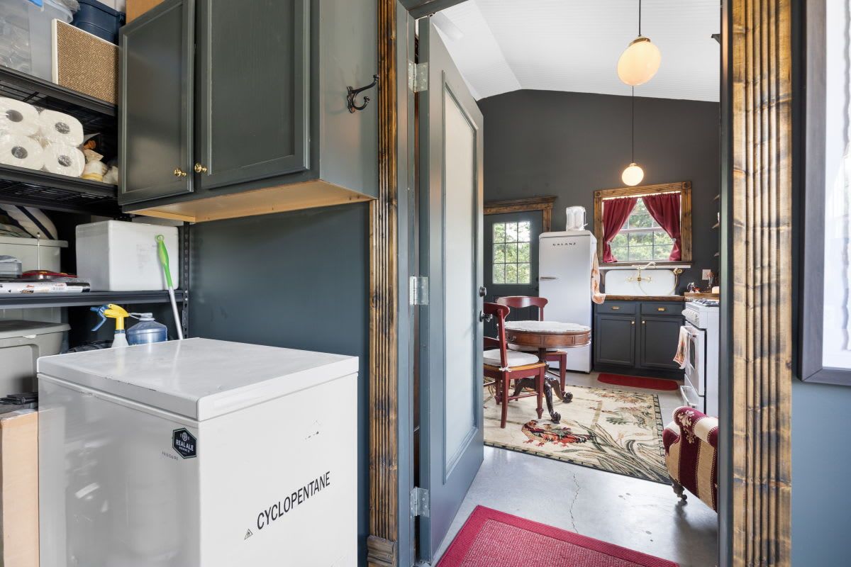 A compact kitchen with dark cabinetry, a white refrigerator, and a dining area with a red rug.