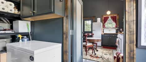 A compact kitchen with dark cabinetry, a white refrigerator, and a dining area with a red rug.