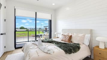 A bedroom with a bed, a nightstand, a ceiling fan, and a view of a green landscape through a sliding door.