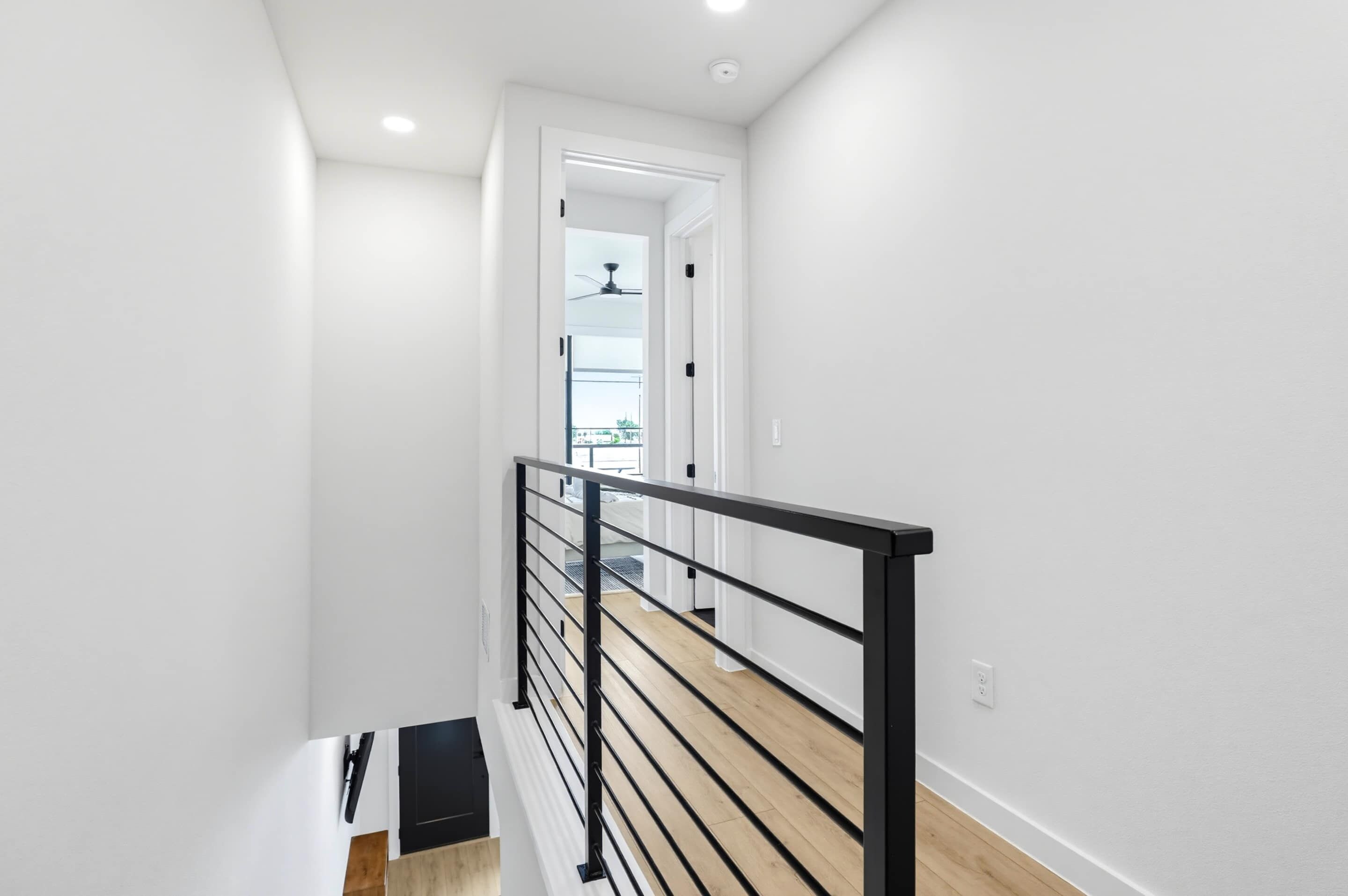 Eine moderne Treppe mit schwarzer Geländer, weißen Wänden und Holzboden.