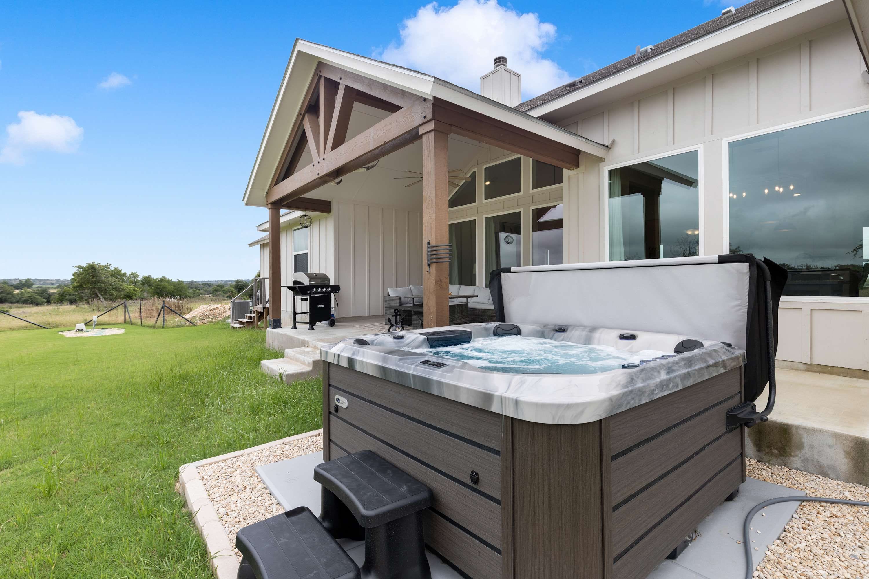 A hot tub with a wooden exterior, a covered patio area, and a view of the surrounding landscape.