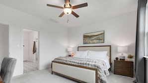 A bedroom with a bed, bedside tables, a ceiling fan, and a painting on the wall. - Birdsong Under the Stars Hot Tub, Fire Pit & Hill Country Views (Fredericksburg)