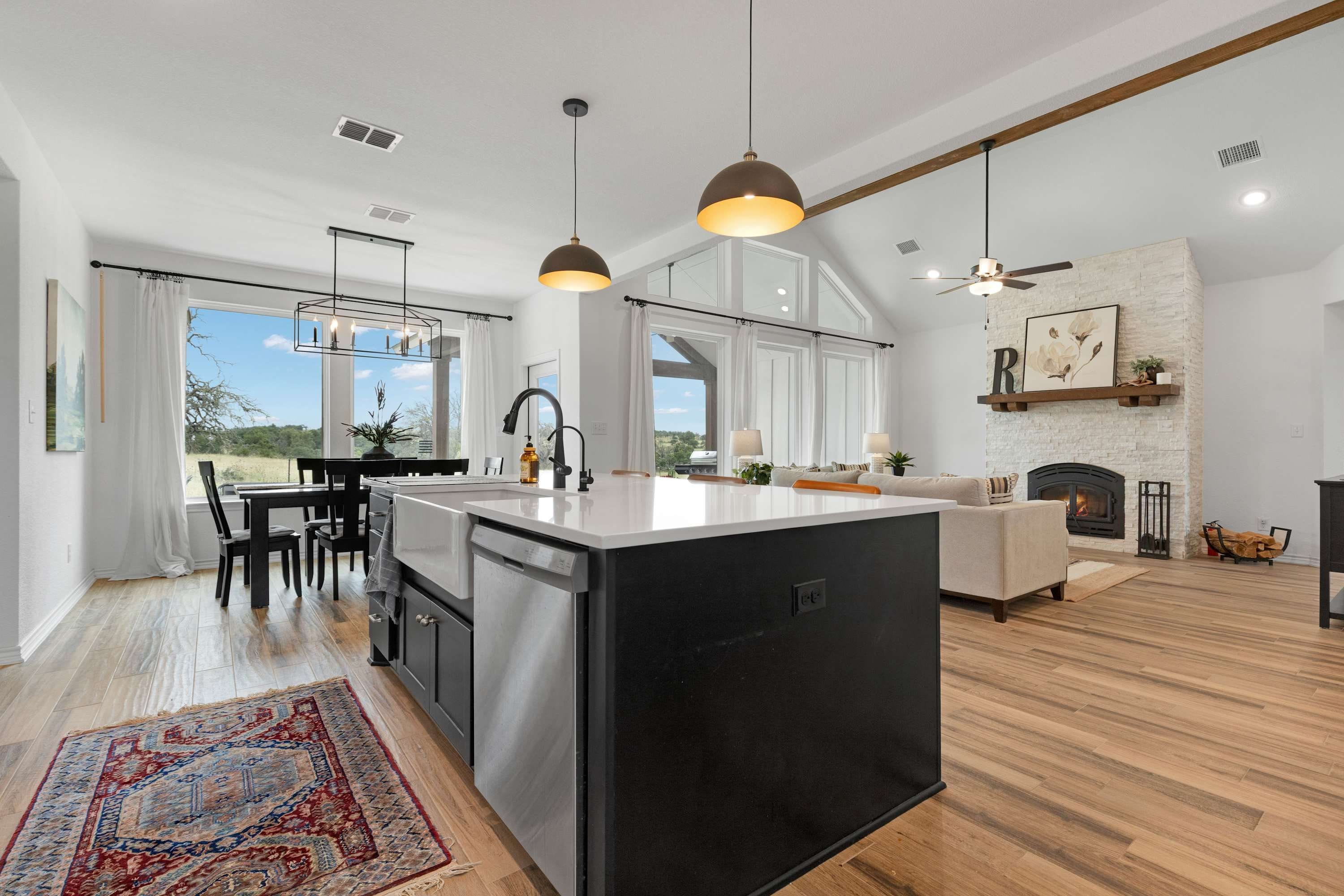 A modern kitchen with a central island, dining area, and a fireplace.