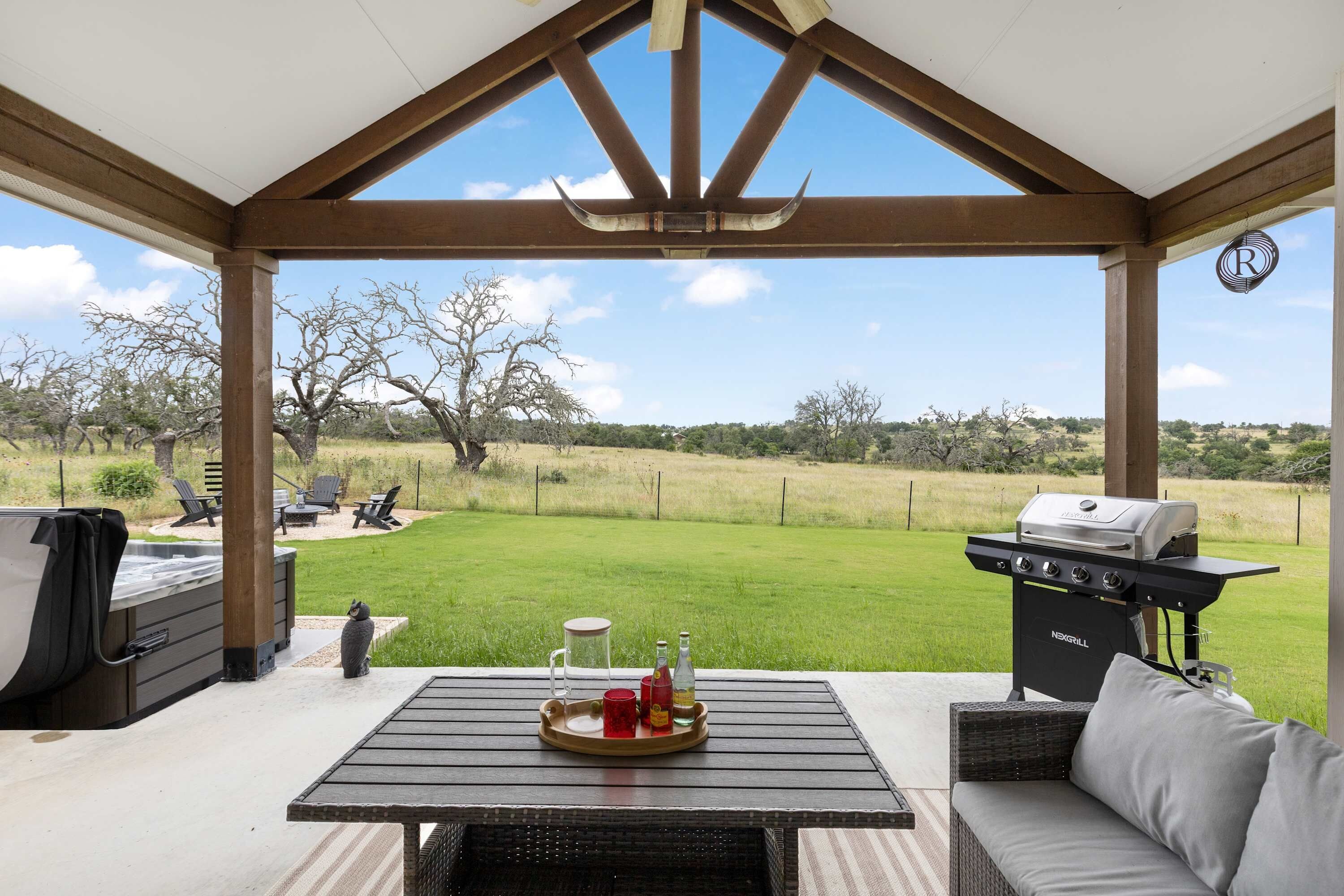 An outdoor patio with a grill, seating, and a view of the yard.