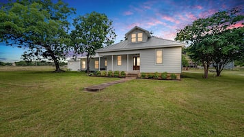A single-story house with a front porch, a small front yard, and a clear sky.