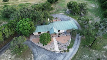 A single-story building with a green roof, surrounded by a gravel driveway and a stone pathway leading to the entrance.