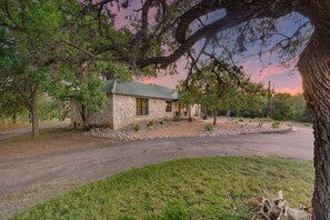 A stone building with a green roof, surrounded by trees and a gravel driveway. - Twisted Cedar Retreat (Ingram)