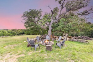 A fire pit surrounded by chairs in an outdoor setting with trees and a clear sky. - Twisted Cedar Retreat (Ingram)